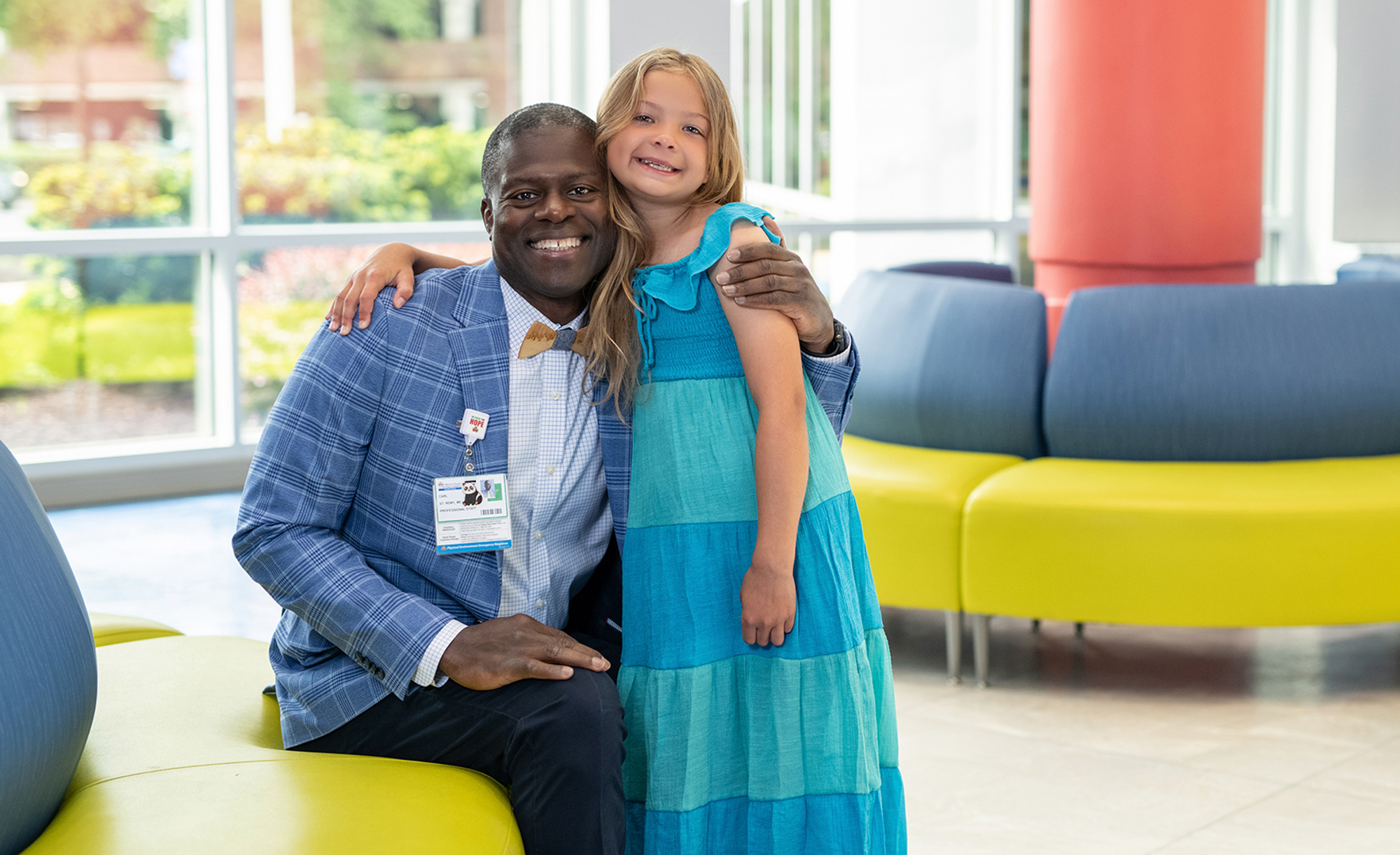 Parker Rose and her doctor, Dr. Carl St. Remy smile happily in the lobby at CHKD.