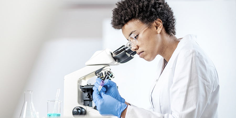 Scientist reviewing lab tests with a microscope.